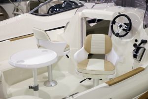 Interior of a boat cockpit featuring a table and two cushioned helm seats. While not visible in this image, boat helm seats are typically designed with features like swivel mechanisms, armrests, and adjustable lumbar support to provide comfort and support for the captain while operating the vessel.